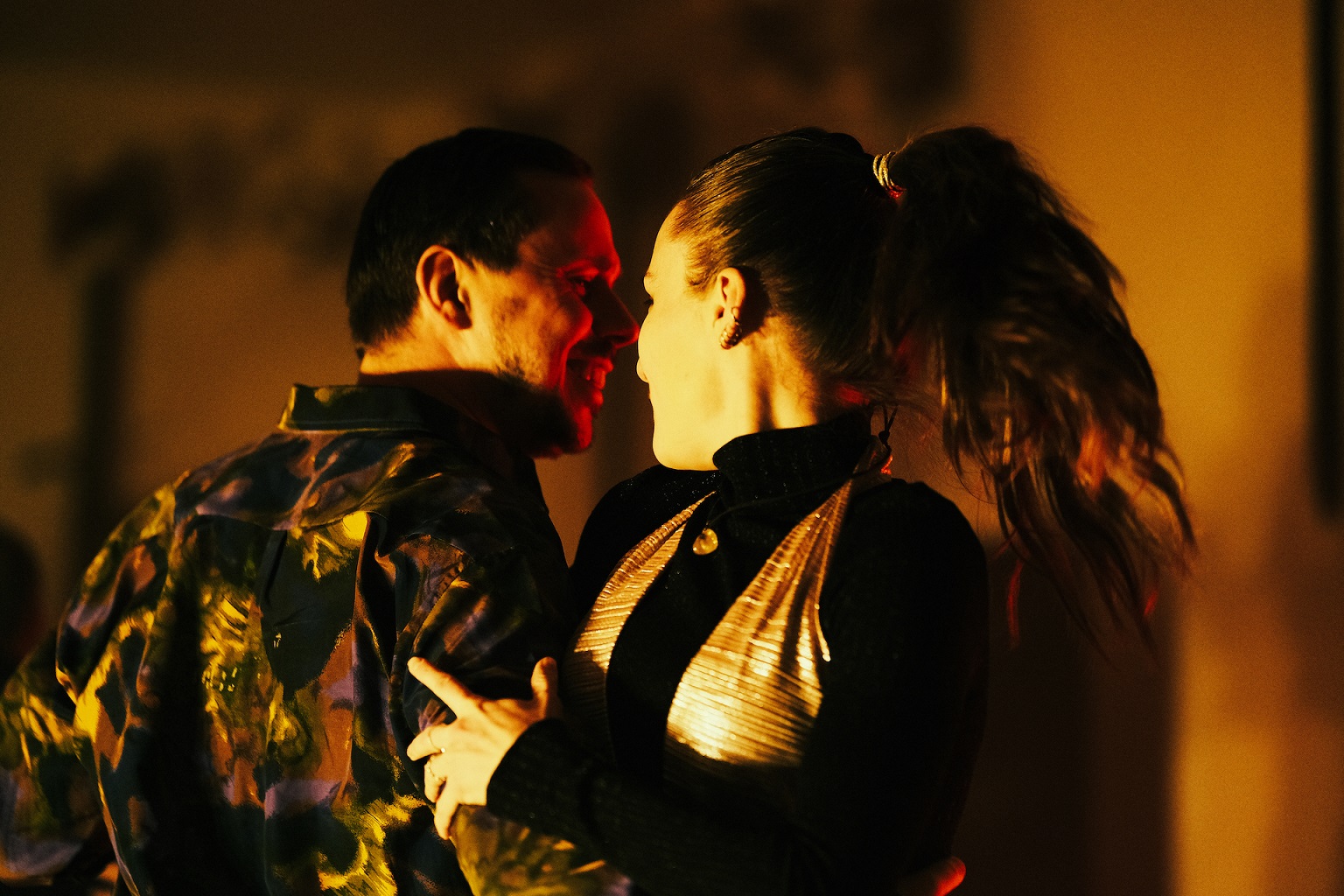 Mężczyzna i kobieta wirują w tańcu w poświacie pomarańczowego światła.