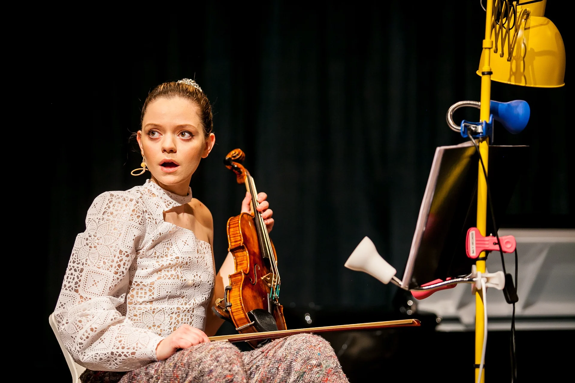 Portret aktorki na scenie ze skrzypcami.