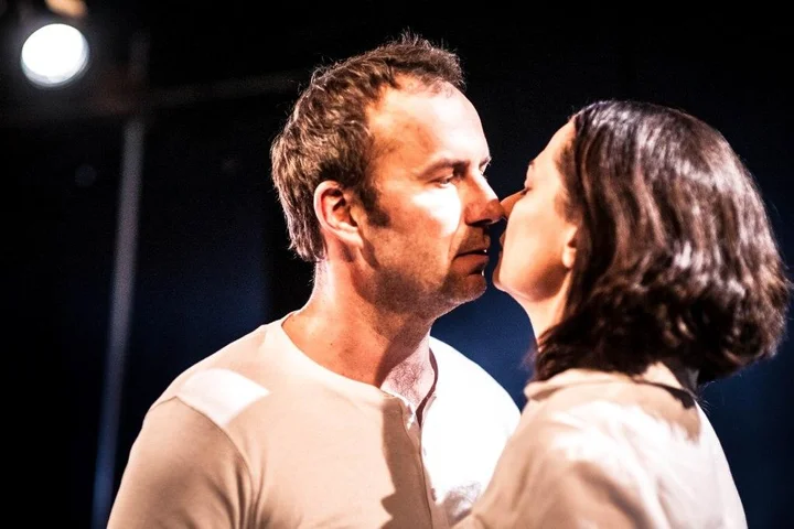 fot. B. Sowa Kobieta i mężczyzna w białych koszulach zbliżają się ustami ku sobie.