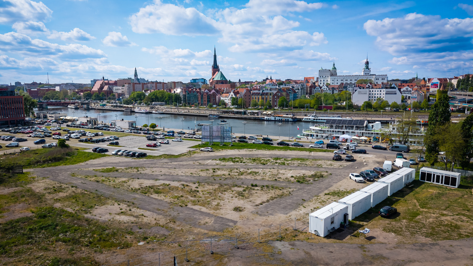 Zdjęcie przedstawia pusty plac po prawej stronie Odry. Na drugim brzegu widoczny Szczecin.