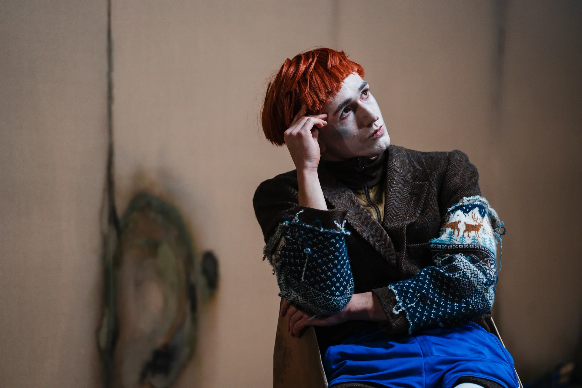 „Very Ibsen”, fot. Piotr Nykowski Mężczyzna w rudej peruce z bladą twarzą. Siedzi na krześle z zamyśloną miną, ręką podpiera skroń.