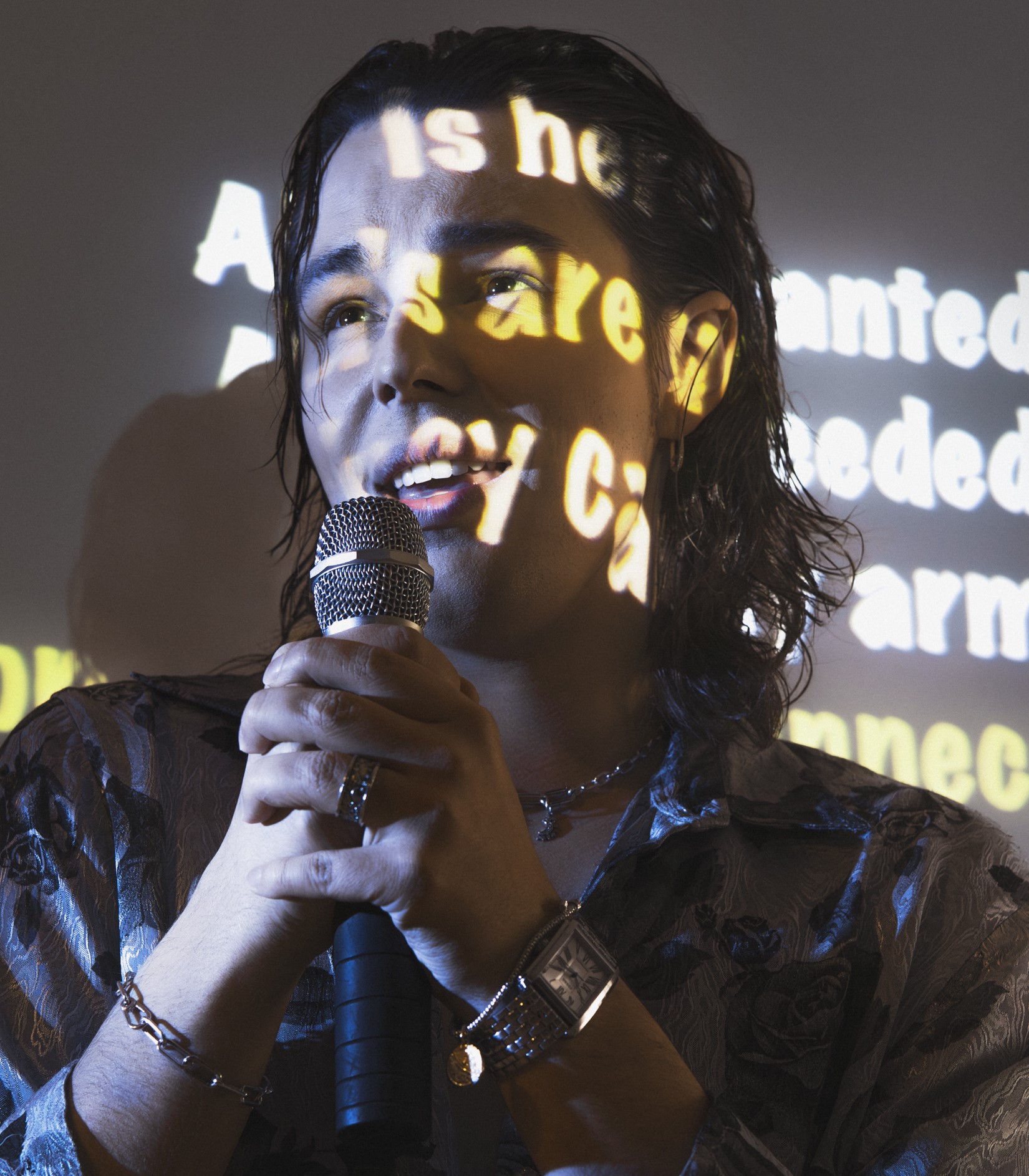 fot. Mila Łapko Młody mężczyzna śpiewa do mikrofonu. Na jego twarzy wyświetlane są słowa piosenki.