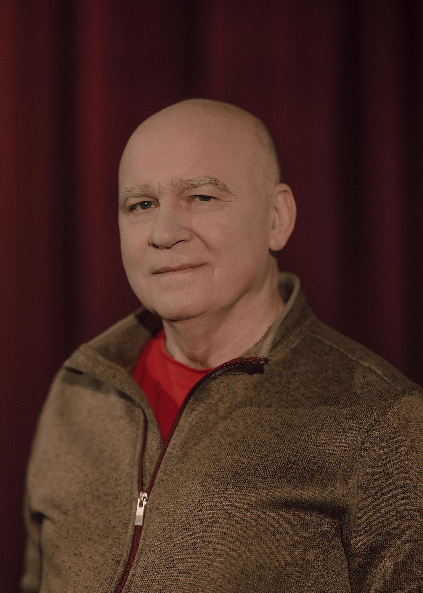 Portret aktora, w tle czerwona kotara.