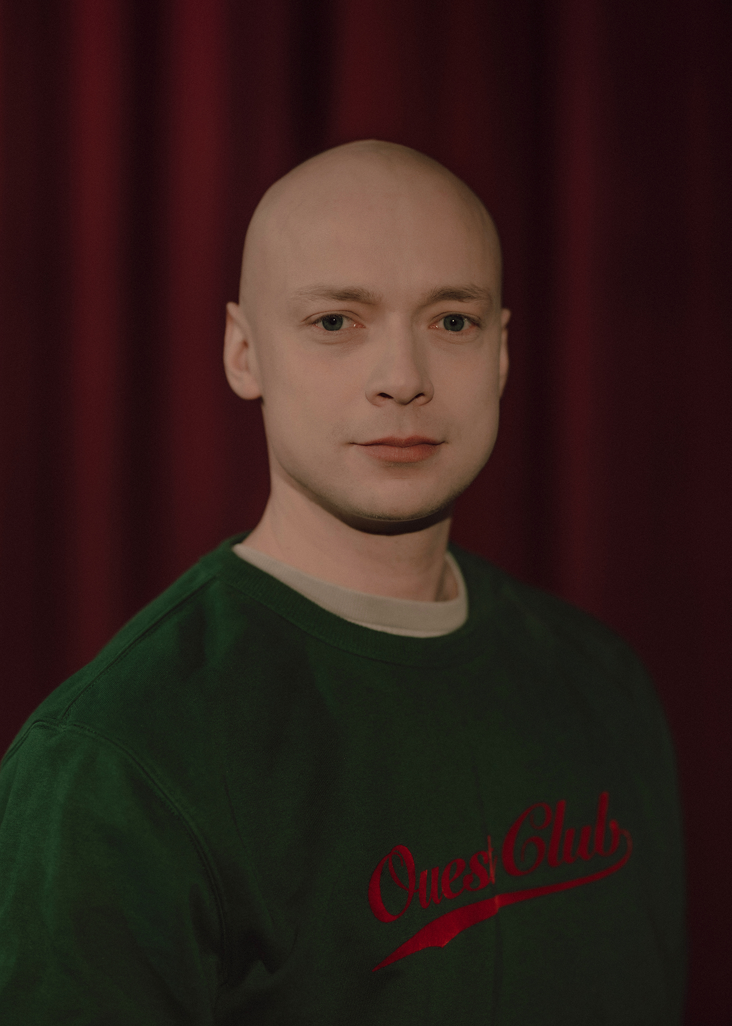 Portret aktora, w tle czerwona kotara.