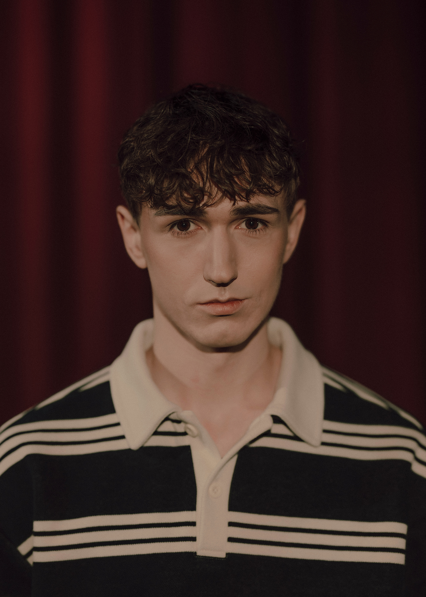 Portret aktora, w tle czerwona kotara.