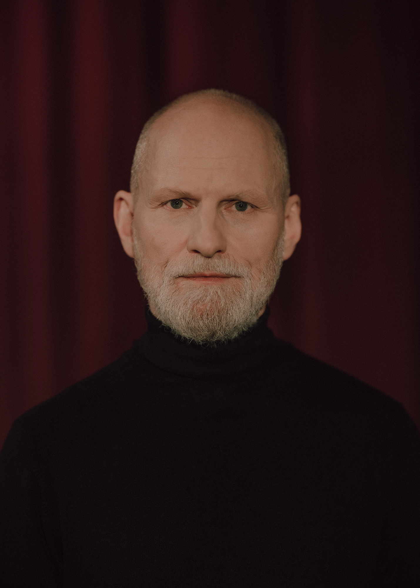 Portret aktora, w tle czerwona kotara.