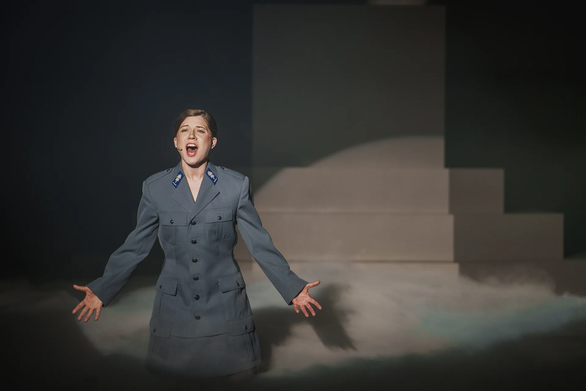 Aktorka ubrana w policyjny mundur śpiewa na scenie. 