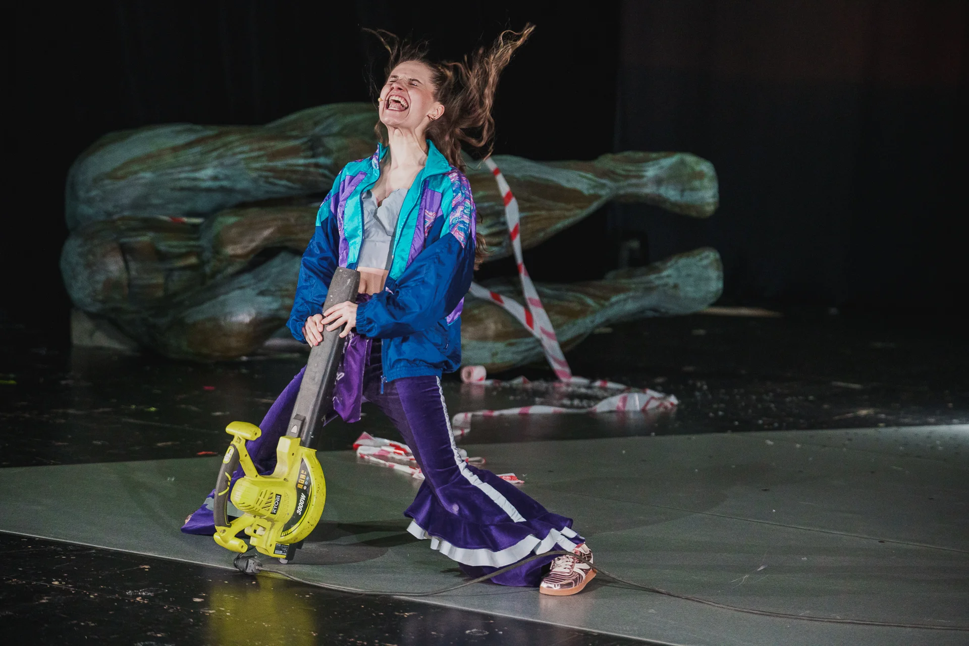 fot. Piotr Nykowski Aktorka na scenie w kolorowym dresie. Na siebie ma skierowaną dmuchawę do liści.
