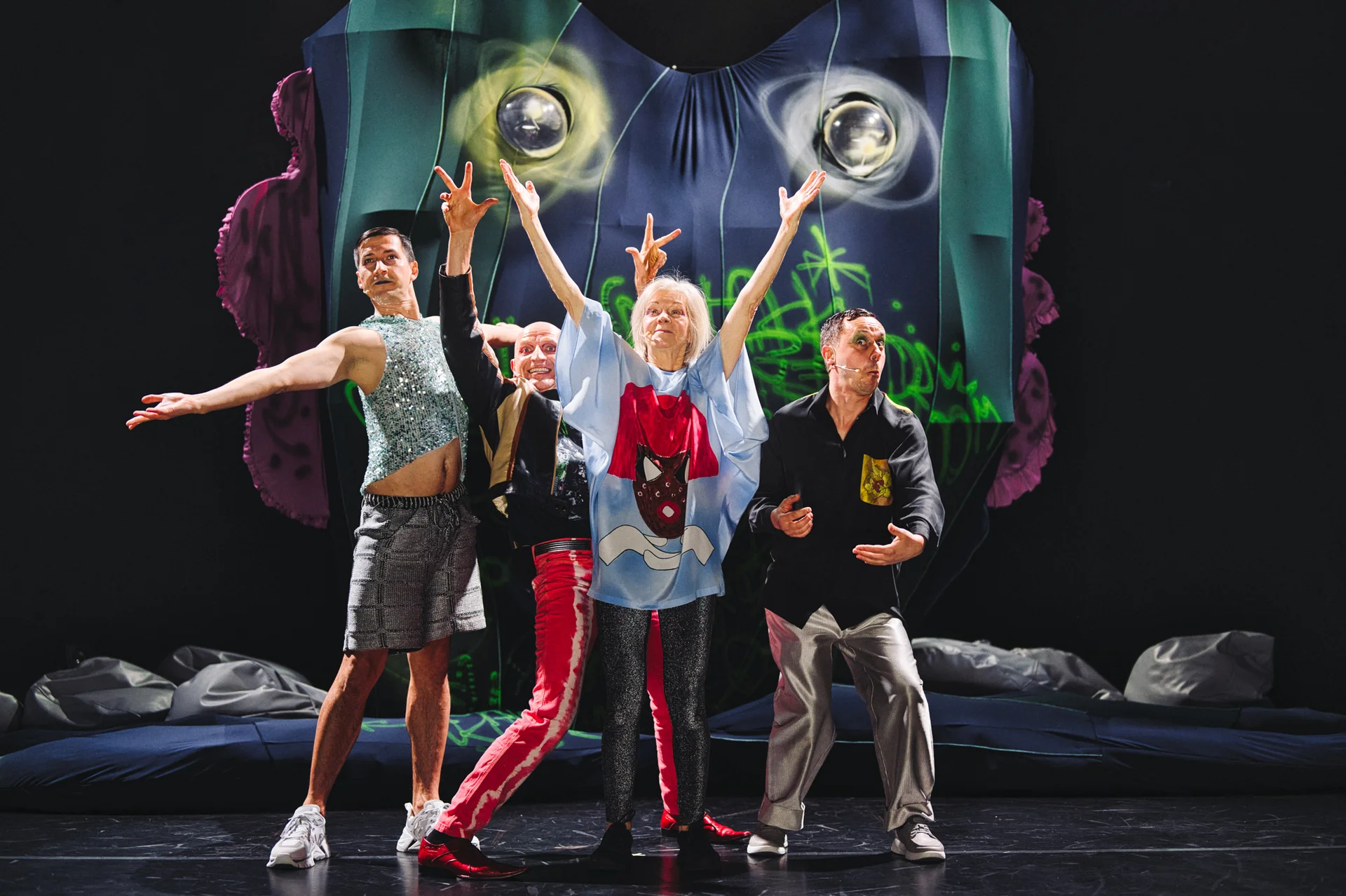 Grupa aktorów na scenie w kolorowych ubraniach.