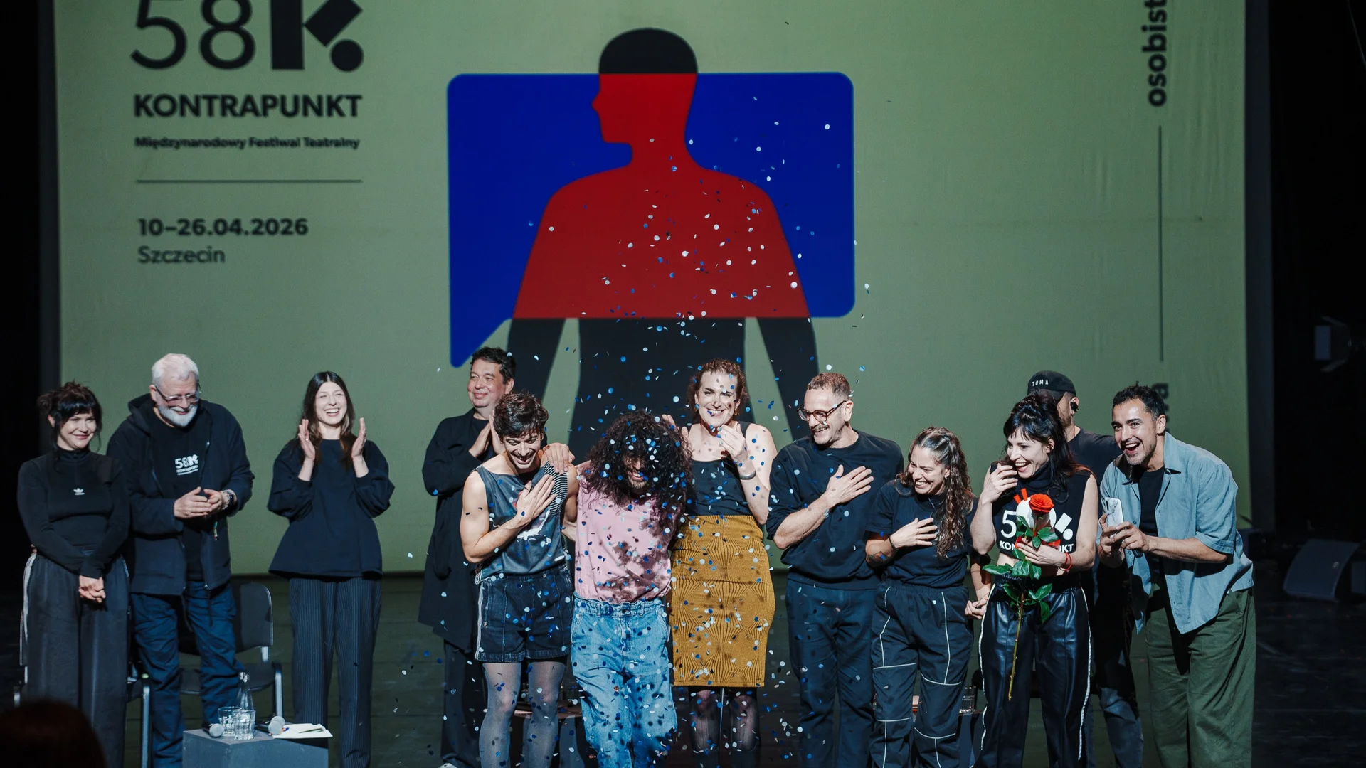 Zdjęcie zwycięzców Grand Prix festiwalu Kontrapunkt. Na scenie stoi grupa osób, w tle widać grafikę z logotypem festiwalu. Przed ludźmi jest wystrzelone kolorowe konfetti. 