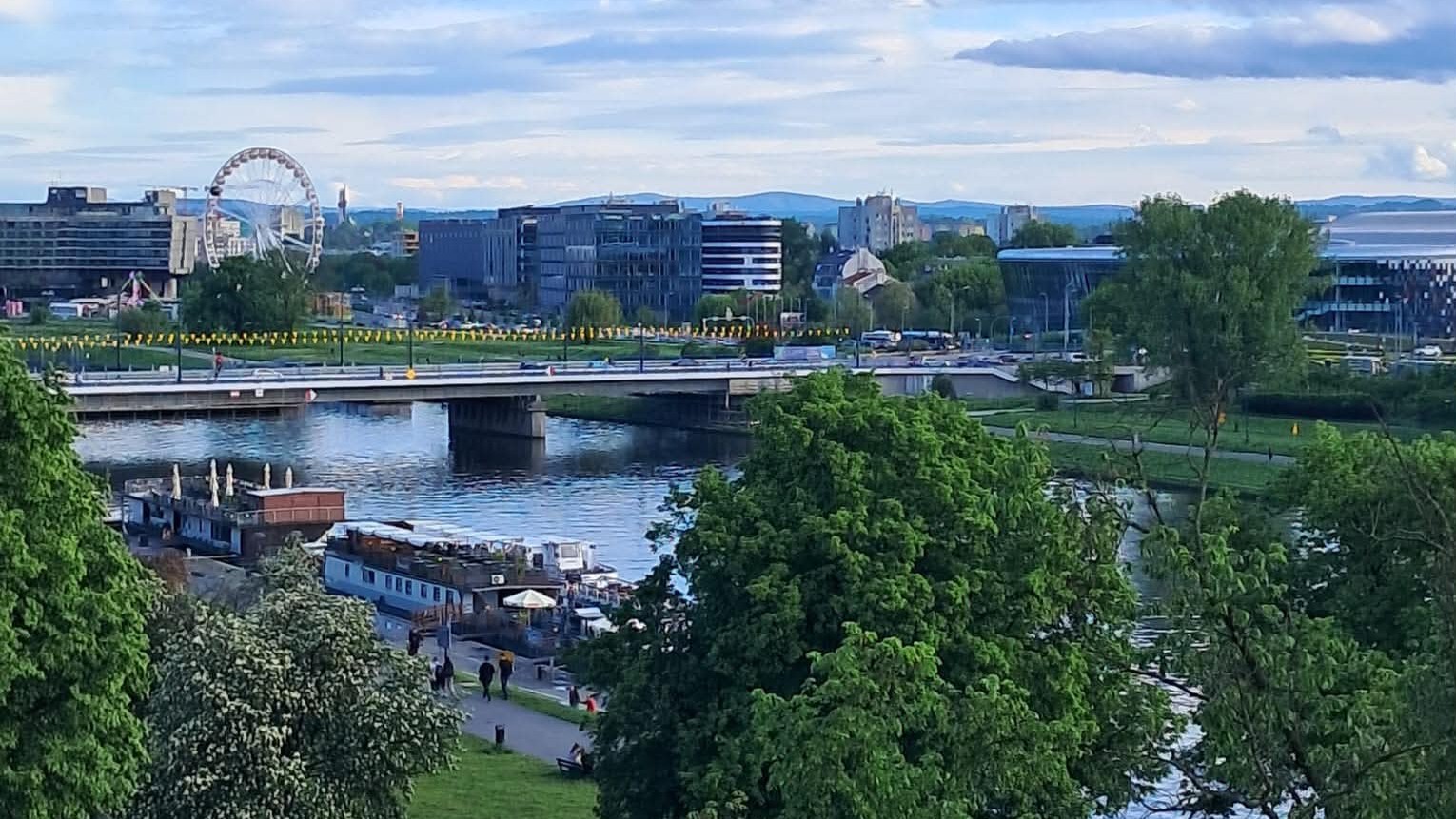 zdjęcie Krakowa zdjęcie Krakowa. Nadwiślańska panorama. Dużo zieleni, most, barka zacumowana przy nabrzeżu, w tle koło diabelskiego młyna.