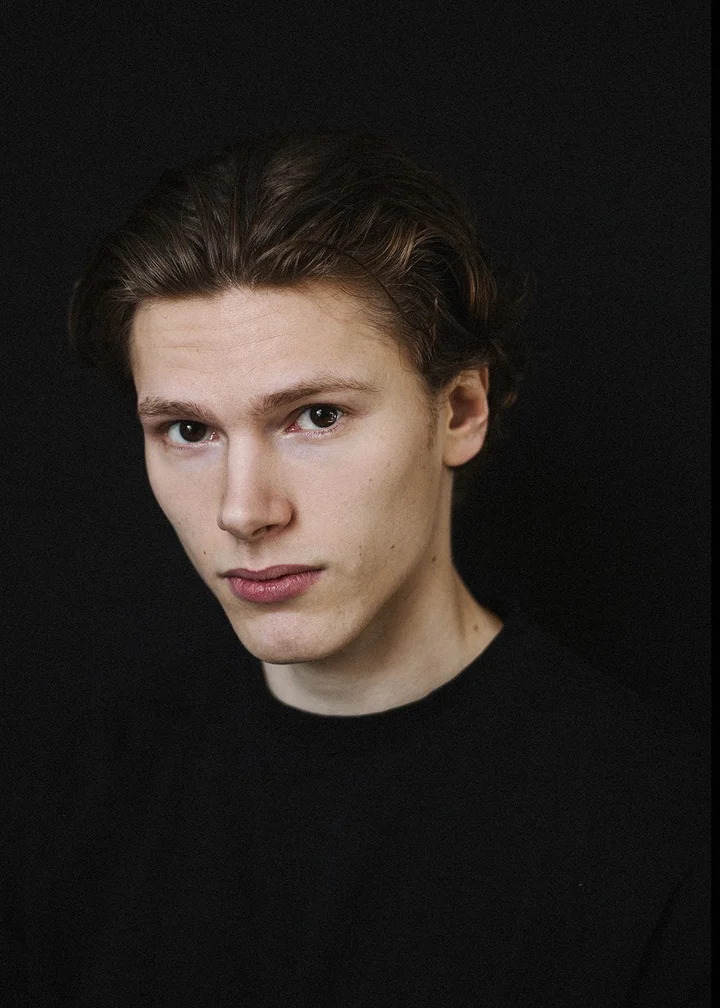 Portret młodego mężczyzny na czarnym tle.